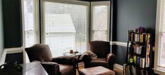 a living room with two brown chairs and a book shelf filled with books on it