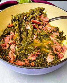 a bowl filled with greens and meat on top of a table