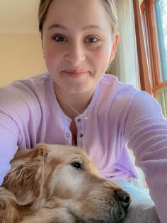 a woman in pink shirt holding a dog on her lap and smiling at the camera