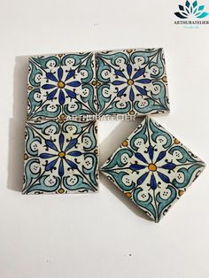 four pieces of blue and white tile sitting on top of a table