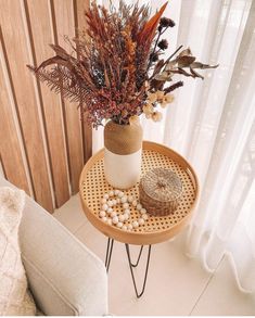 there is a vase with flowers and rocks on the table next to the window sill