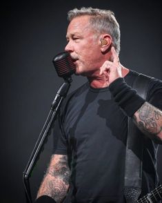 a man with tattoos on his arm holding a microphone