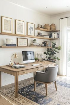 a desk with a computer on top of it next to a chair and bookshelf