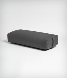 a gray pillow sitting on top of a white floor