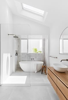 a bathroom with two sinks and a bathtub under a skylight in the corner