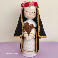 a crocheted doll with a heart in her hand on a purple table top