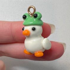 a tiny white bird with a green hat on it's head sitting on someones finger