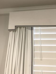 an open window with white curtains and blinds