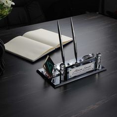 a desk with an open book, pen and knife sharpener on top of it