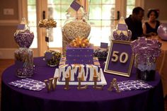 a purple table topped with lots of candy and candies next to a sign that says 50