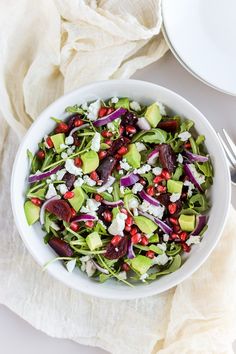 a white bowl filled with salad on top of a table next to a fork and napkin