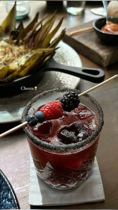 a red drink with berries on the rim and a strawberries garnish in it