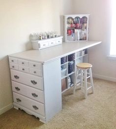 a white desk with drawers and two stools next to it in a room that has carpet on the floor