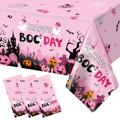 a pink table cloth with halloween decorations on it and the words happy boo day written in black