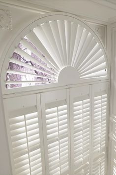 an arched window with white shutters in a room