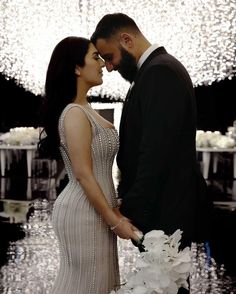 a man and woman standing next to each other in front of a chandelier