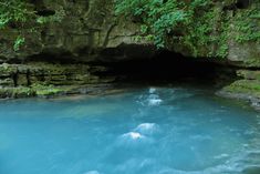 the water is blue in color and it looks like they are going into a cave