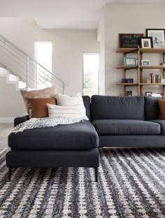 a living room filled with furniture and bookshelves next to a stair case on the wall