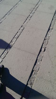 a person riding a skateboard down a street next to a cement sidewalk with cracks in it