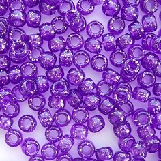 purple glass beads are shown on a white surface with no other beads in the background