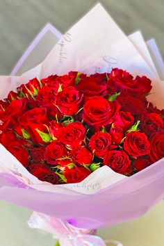 a bouquet of red roses is wrapped in pink paper and ready to be given as a gift