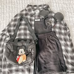 mickey mouse handbag and other items laid out on a bed