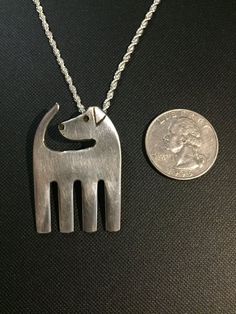 a small silver dog necklace next to a dime