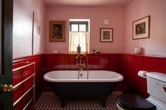 an old fashioned bathtub in a red and black bathroom