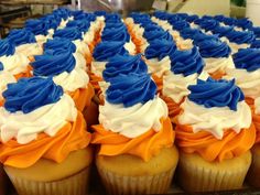 cupcakes with blue, white and orange frosting are arranged on a table