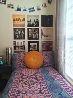 a bed in a room with pictures on the wall above it and an orange pillow