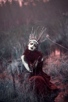 a woman in black and white is sitting in the grass with her headdress on