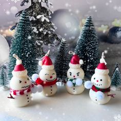 three snowmen with hats and scarfs are standing in front of christmas tree decorations