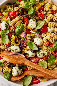 a pasta salad with tomatoes, mozzarella and spinach