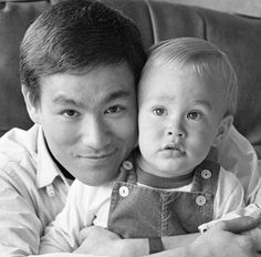 a black and white photo of a man holding a baby in his lap, with the child's face on top of him