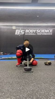 a man kneeling down on top of a skateboard in front of a sign that says body science baseball performance