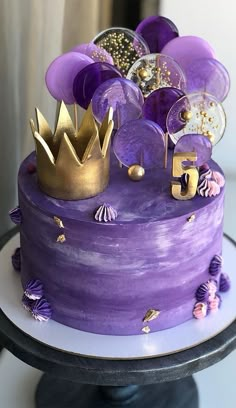 a cake with purple frosting and gold decorations on the top is sitting on a table