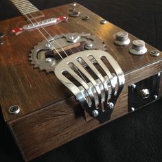 a wooden box with metal parts and a guitar on it's back side, sitting on a black surface