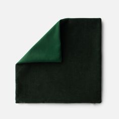 a dark green blanket folded on top of a white surface