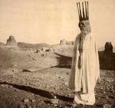 an old black and white photo of a man with a crown on his head in the desert