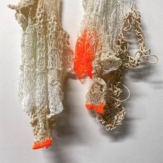 there are two pieces of crocheted material on the wall, one orange and one white