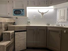 a kitchen with white cabinets and an animal head on the wall