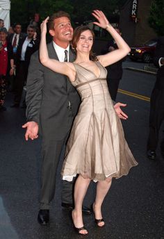 a man and woman in formal wear dancing on the street with their arms around each other