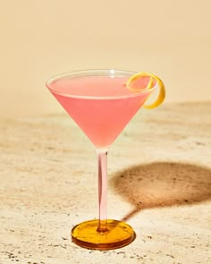 a pink cocktail with an orange slice on the rim