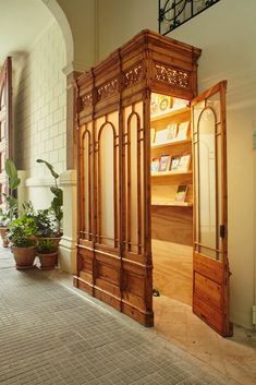 a wooden cabinet sitting in the middle of a room next to a potted plant