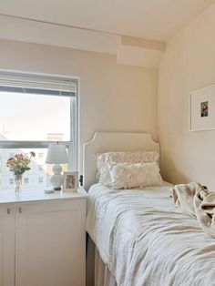 a white bed sitting next to a window in a bedroom