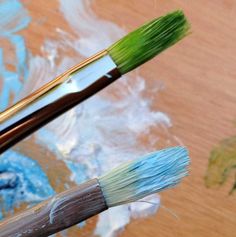 two paintbrushes sitting on top of a wooden table