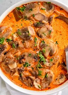 a white bowl filled with mushroom soup and garnished with parsley