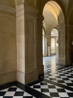 a hallway with black and white checkered flooring, arched doorways and arches