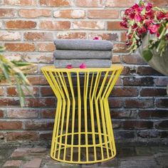 a yellow side table with towels on top and flowers in the back ground next to it