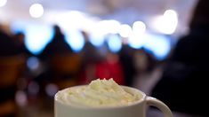 a white cup filled with whipped cream on top of a table